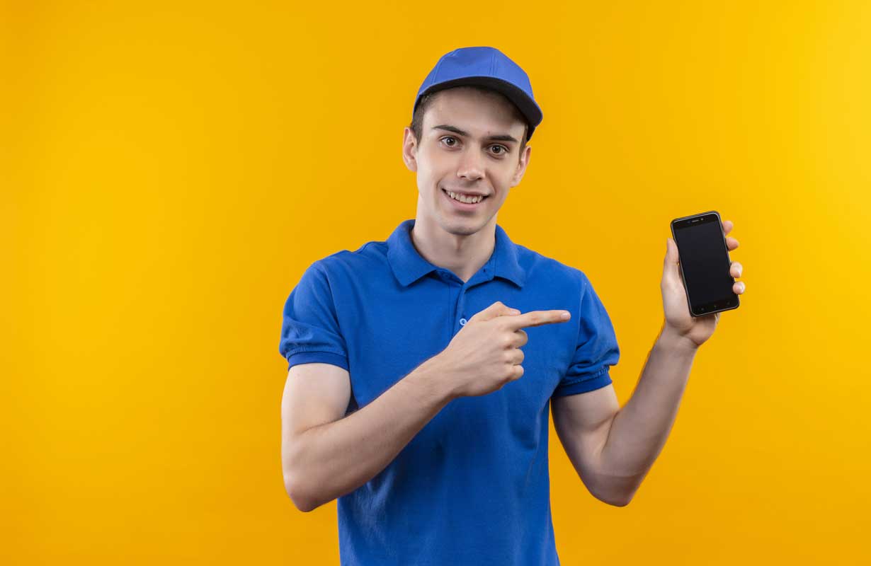 Um técnico de celular apontando para um aparelho na outra mão ilustra nosso artigo sobre: abrir assistência técnica de celular. Créditos da imagem: freepik.com Um técnico de celular apontando para um aparelho na outra mão ilustra nosso artigo sobre: abrir assistência técnica de celular. Créditos da imagem: freepik.com